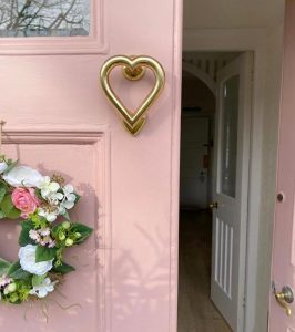 pink external wooden door with brass heart knocker
